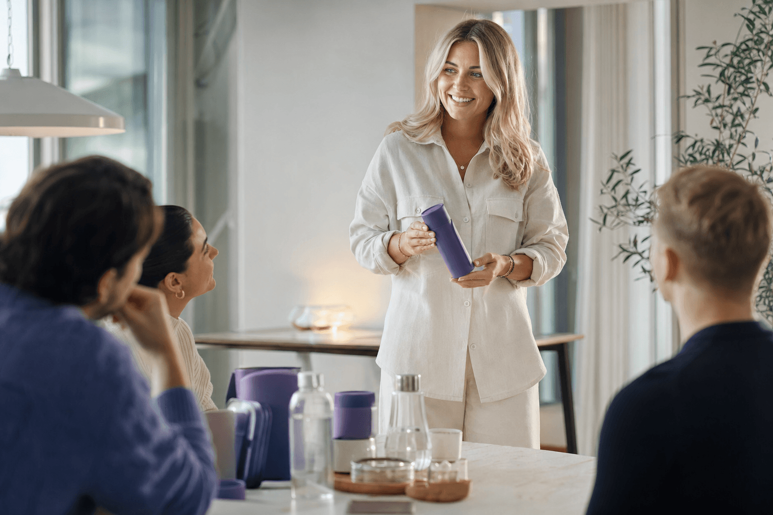 Markedssjef presenterer ny produktlansering for et lite team rundt et bord med produktprøver