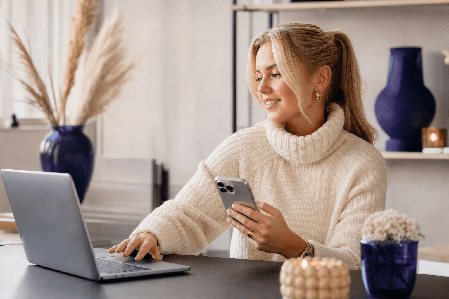 Influencer som jobber ved en laptop med telefon og notater i et lyst og profesjonelt arbeidsmiljø
